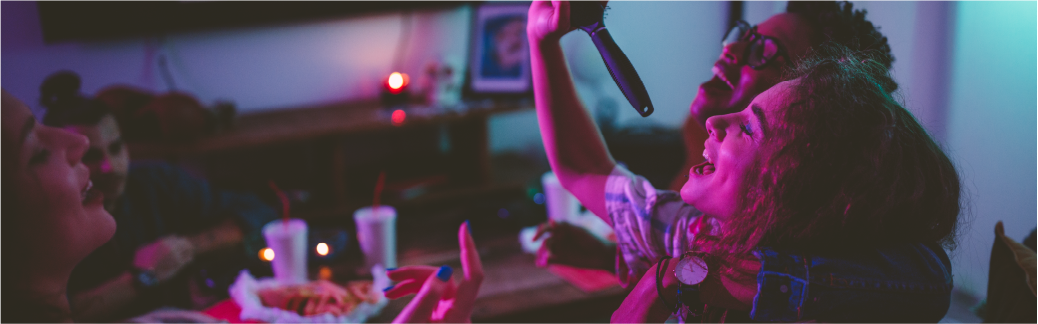 group of friends laughing at home using hair brush as a microphone